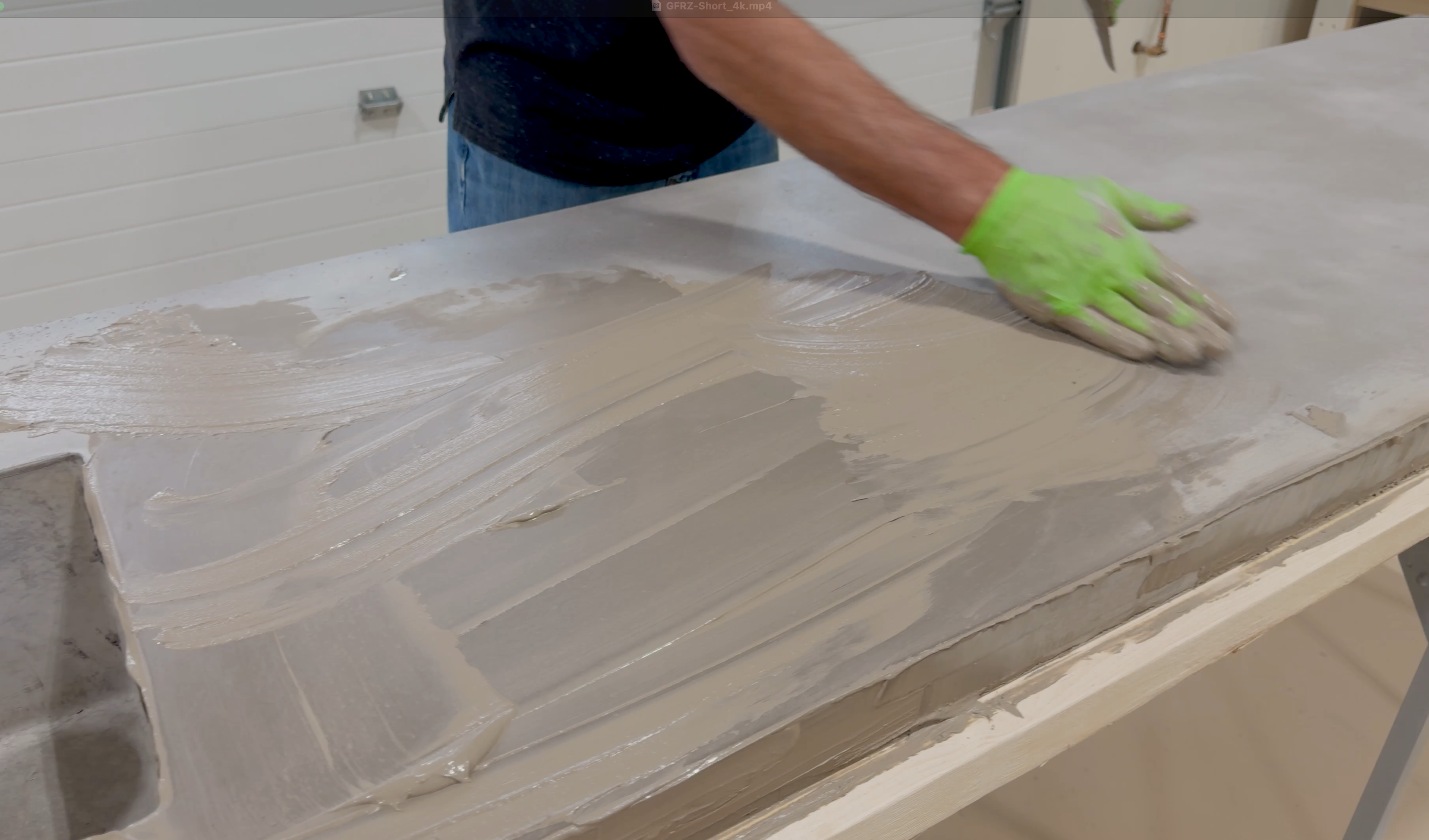 Worker applying Patch Pro slurry mix to a concrete countertop surface, smoothing out imperfections and filling voids for a flawless finish.